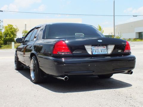 2003 Ford Crown Victoria - Left rear 3/4; blacked-out sedan, black wheels, single exhaust tip shown, EVIL VIC plate