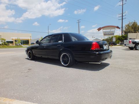 2003 Ford Crown Victoria - Left rear 3/4 streetside; lowered black sedan, black wheels, SIMCO Plating sign behind