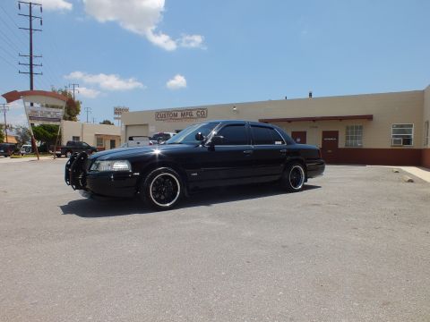 2003 Ford Crown Victoria - Front three-quarter of a lowered black sedan fitted with a push bar and black rims.