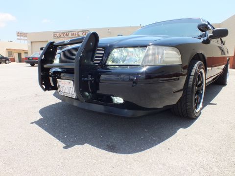 2003 Ford Crown Victoria - Wide-angle low view of a black sedan front bumper, grille guard and black wheel.