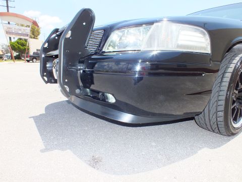 2003 Ford Crown Victoria - Detail of a black sedan's lowered front bumper, headlight and grille guard bracket.