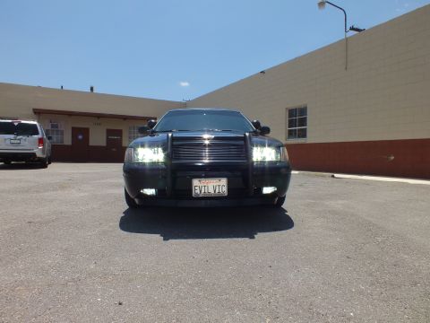 2003 Ford Crown Victoria - Front of a black sedan with headlights on, billet grille and EVIL VIC plate.