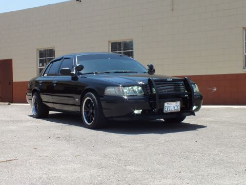 2003 Ford Crown Victoria - Black Crown Victoria angled toward camera with push bar and EVIL VIC plate.