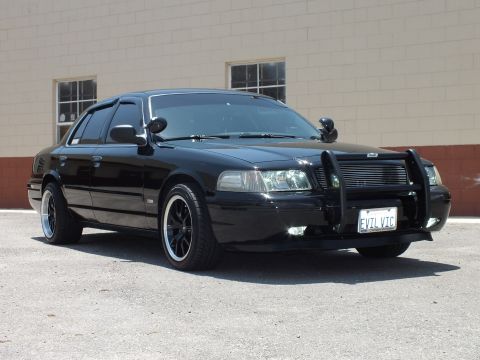 2003 Ford Crown Victoria - Front-quarter view of a lowered black Crown Victoria with billet grille and push bar.