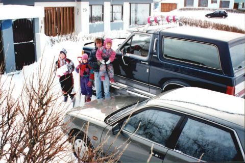1996 Ford Bronco - A family poses with their Ford Bronco in a snowy driveway, with another car partially visible.