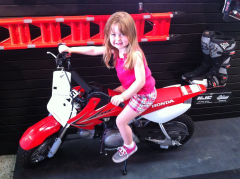 1978 Ford Bronco - A young girl poses on a red Honda dirt bike, with motocross boots displayed nearby.