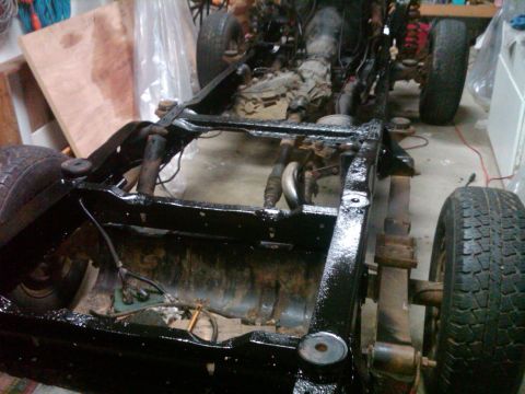1986 Ford Bronco - The chassis of a vehicle is shown with its engine and suspension parts, likely during a rebuild process.