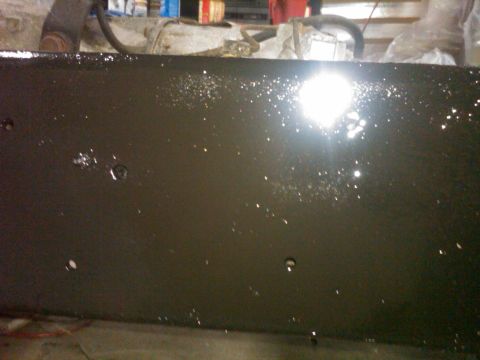 1986 Ford Bronco - Close-up of a dark painted metal frame, possibly part of a vehicle undergoing repair.