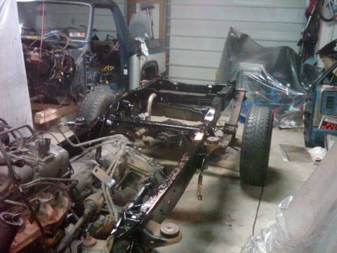 1986 Ford Bronco - The chassis and engine of a vehicle are visible in a garage, suggesting a rebuild or restoration project is underway.