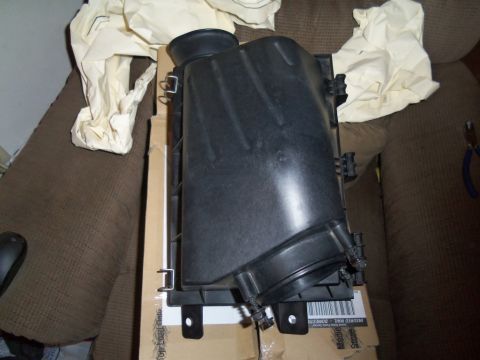 2000 Mercury Grand Marquis - A black plastic air filter housing sits on top of a cardboard box, partially covered by a light-colored cloth.