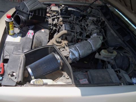 2000 Mercury Grand Marquis - The engine bay of a car is shown with the hood open, revealing the engine and an aftermarket air intake system.