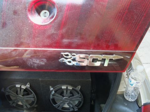 2000 Mercury Grand Marquis - The trunk of a red car displays an SCT badge and aftermarket speakers.