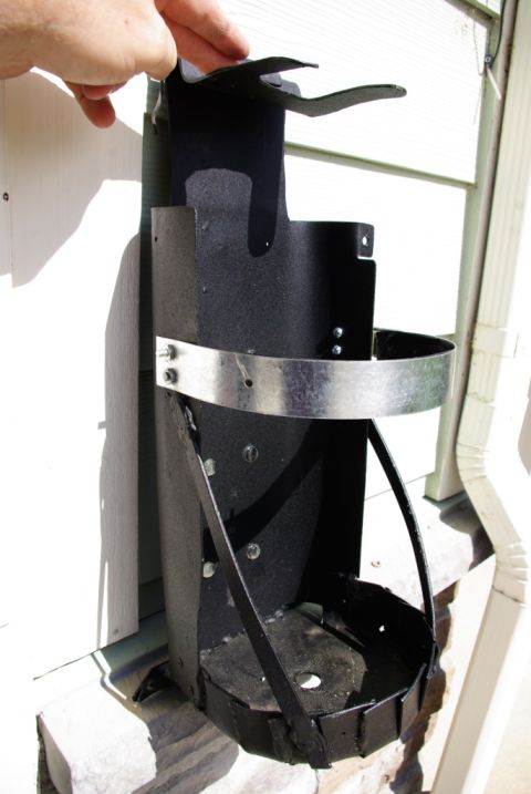 1995 Ford Bronco - A black metal fire extinguisher mount is shown attached to a wall, with a hand holding the top bracket.