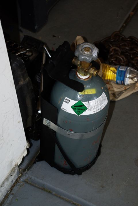 1995 Ford Bronco - A gray carbon dioxide tank is secured with straps, showing various warning labels and a valve at the top.