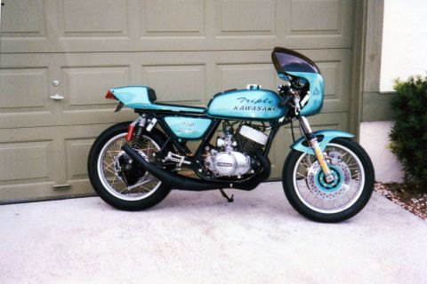 1999 Ford Ranger - Light blue Kawasaki motorcycle with fairing and "Triple KAWASAKI 750" text parked in front of a garage.