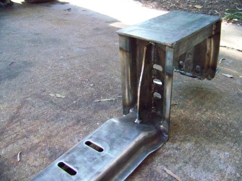 1985 Ford Bronco - A fabricated metal bracket with visible welds and mounting holes is shown on a concrete surface.