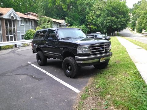1995 Ford Bronco - Black 1995 Ford Bronco XLT parked in a lot with a residential building and trees nearby.