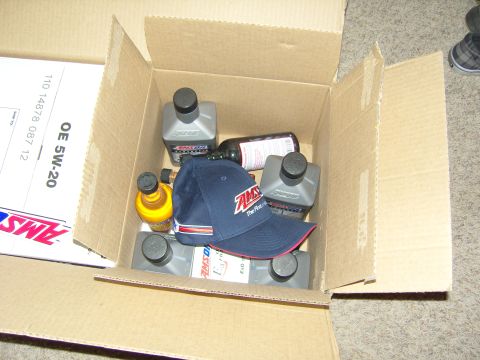 2007 Ford Mustang - A cardboard box contains several bottles of AMSOIL motor oil and an AMSOIL branded baseball cap.