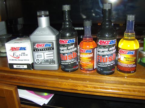 2007 Ford Mustang - Collection of AMSOIL automotive fluids and an oil filter displayed on a wooden surface.