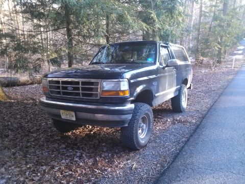 1995 Ford Bronco - This 1995 Ford Bronco is parked on the side of a road in a wooded area.
