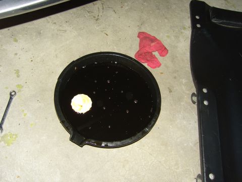 2007 Ford Mustang - An oil drain pan holds used oil and a filter, with a red rag and wrench nearby on a concrete surface.