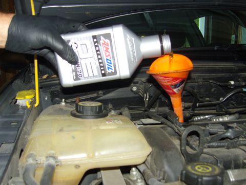 2007 Ford Mustang - Pouring AMSOIL synthetic 5W-20 oil into a vehicle's engine bay via an orange funnel.