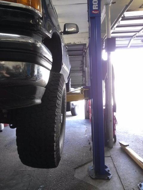 1995 Ford Bronco - A dark blue 1995 Ford Bronco XLT is shown from the side while elevated on a car lift in a garage.