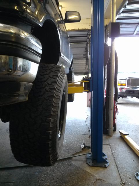 1995 Ford Bronco - Side view of a 1995 Ford Bronco XLT on a lift in a garage, with another Bronco in the background.