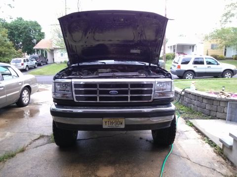 1995 Ford Bronco - A Ford F-Series truck is parked in a driveway with its hood up, showing the engine bay.