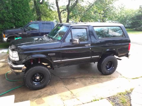 1995 Ford Bronco - Black 1995 Ford Bronco parked outdoors next to a blue Ford F-Series truck.