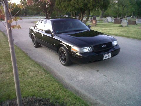 1999 Ford Crown Victoria - A black 1999 Ford Crown Victoria is parked on a road in a cemetery.