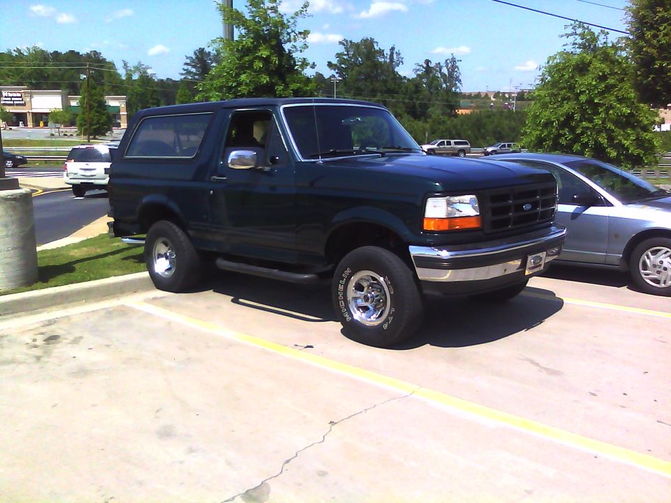 Dark green Ford Bronco parked in a lot, next to a silver car