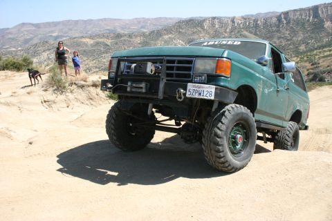 1991 Ford Bronco - Modified 1991 Ford Bronco driving off-road in a desert landscape.