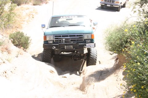 1991 Ford Bronco - Green 1991 Ford Bronco tackles a challenging off-road trail with a second Bronco in the distance.