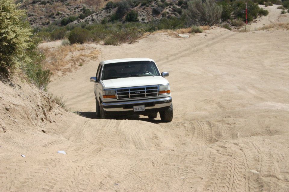 White Ford F-Series truck driving on a sandy dirt road