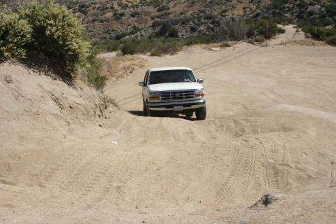 1991 Ford Bronco - This white Ford F-Series truck navigates a dusty, off-road trail.