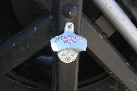 1991 Ford Bronco - A bottle opener is mounted on a dark metal structure, with text indicating 'OPEN BOTTLE HERE'.