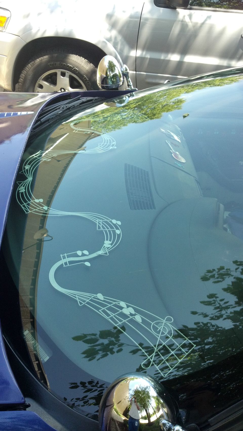 Windshield with musical notes decal. Another vehicle is visible in the background