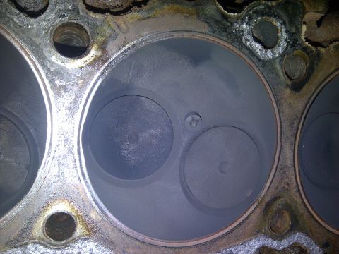 1986 Ford Bronco - Close-up view of an engine's cylinder head, revealing internal components and signs of wear.