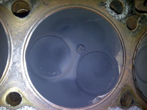 1986 Ford Bronco - Close-up of an engine cylinder head with valves and carbon buildup.