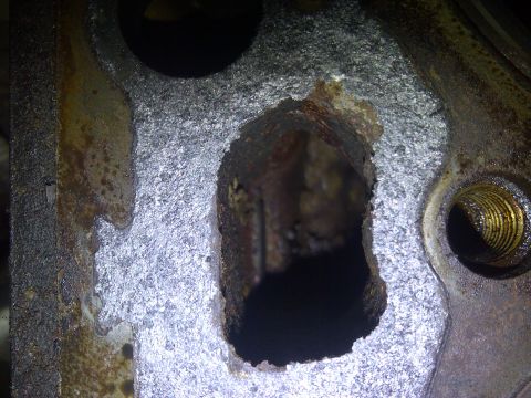 1986 Ford Bronco - This heavily corroded engine part shows significant damage and rust.