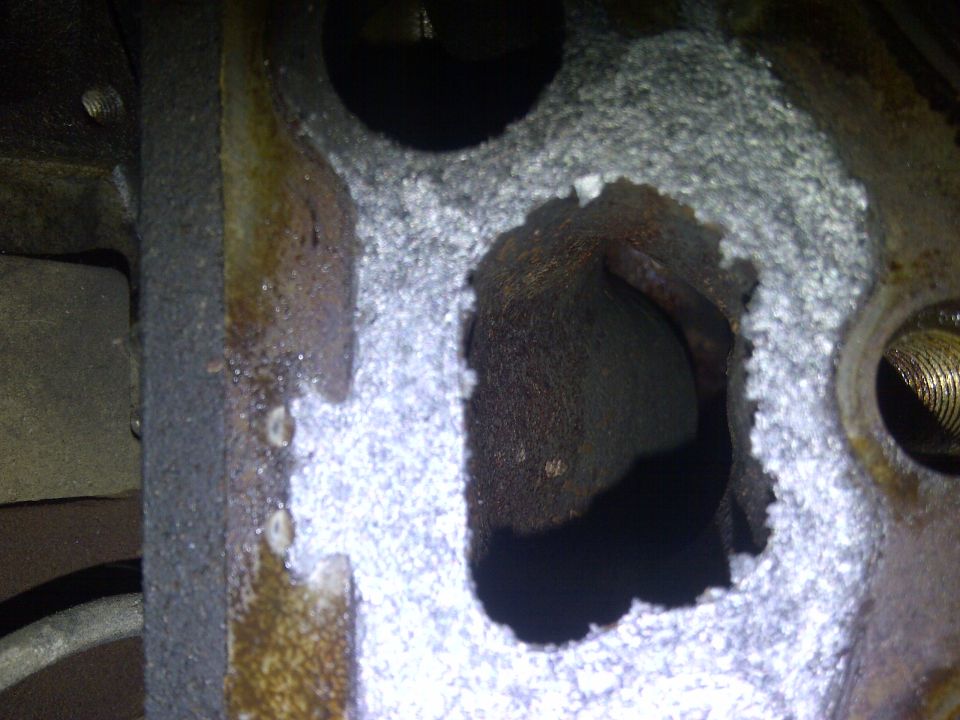 Close-up of damaged engine cylinder head with corrosion and a hole