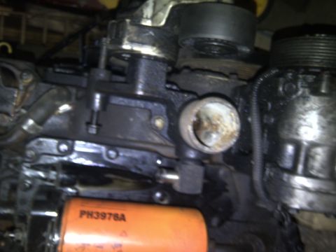1986 Ford Bronco - An orange oil filter is visible in front of a dark engine component, with some text on the filter.