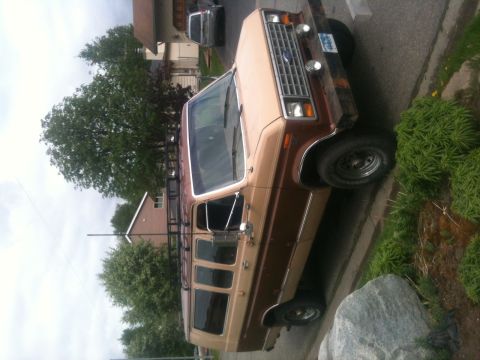 1990 Chevrolet Suburban - A two-tone Ford Econoline van with a roof rack is parked on the side of a residential street.