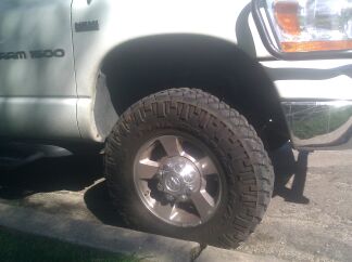 1989 Ford Bronco - Close-up of a white Dodge Ram 1500 truck's front wheel and fender area.