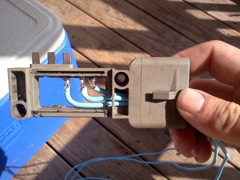 1989 Ford Bronco - Hand holds a disassembled electrical connector with exposed wires and terminals.