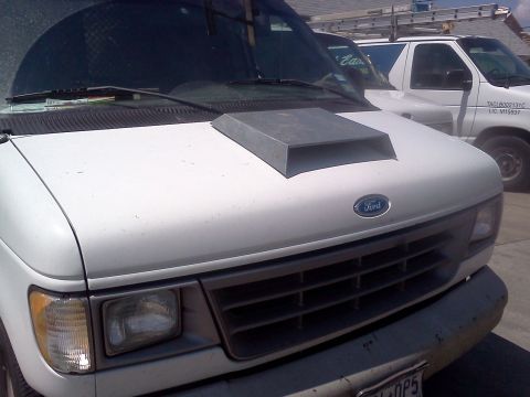 1989 Ford Bronco - A white Ford van with a custom hood scoop is parked next to another van.