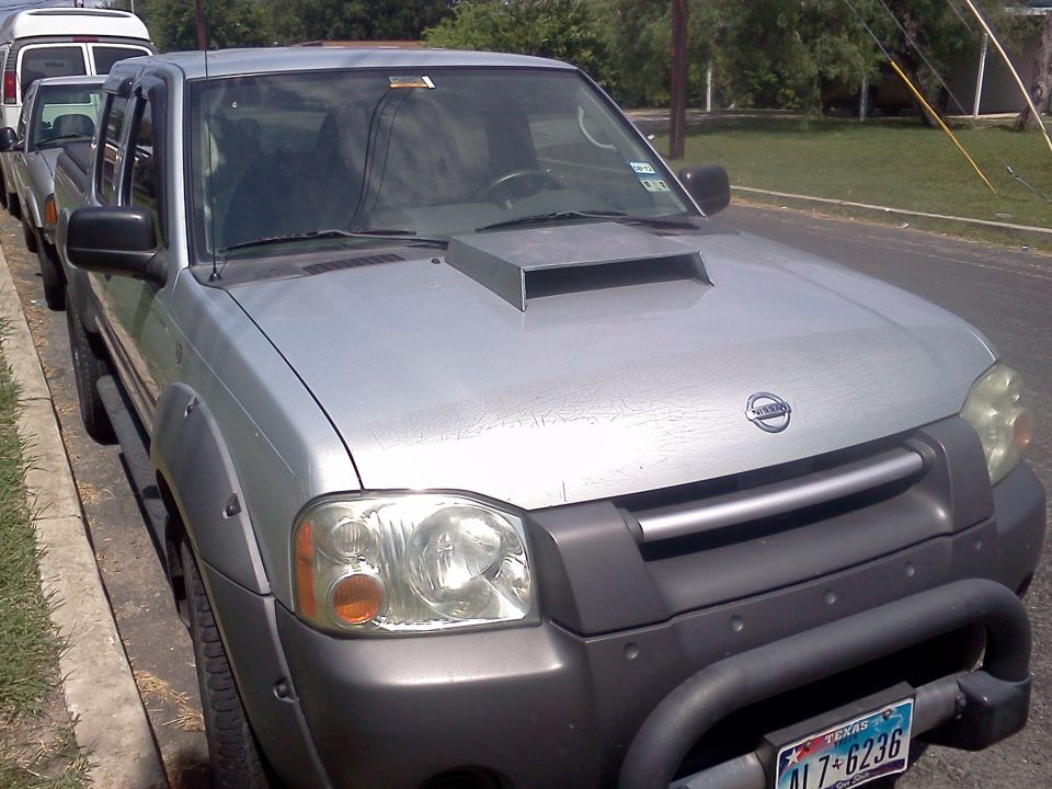 Silver Nissan pickup truck with a hood scoop and fender flares parked on a street
