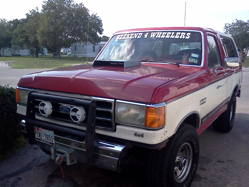 Red and white 1989 Ford Bronco with hood scoop and off-road lights