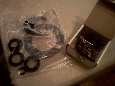 1989 Ford Bronco - Transmission shift fork and seals laid out on a surface, some parts in packaging and a small box.
